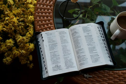 An open Bible with Chinese text, placed on a table with yellow flowers and a coffee mug.